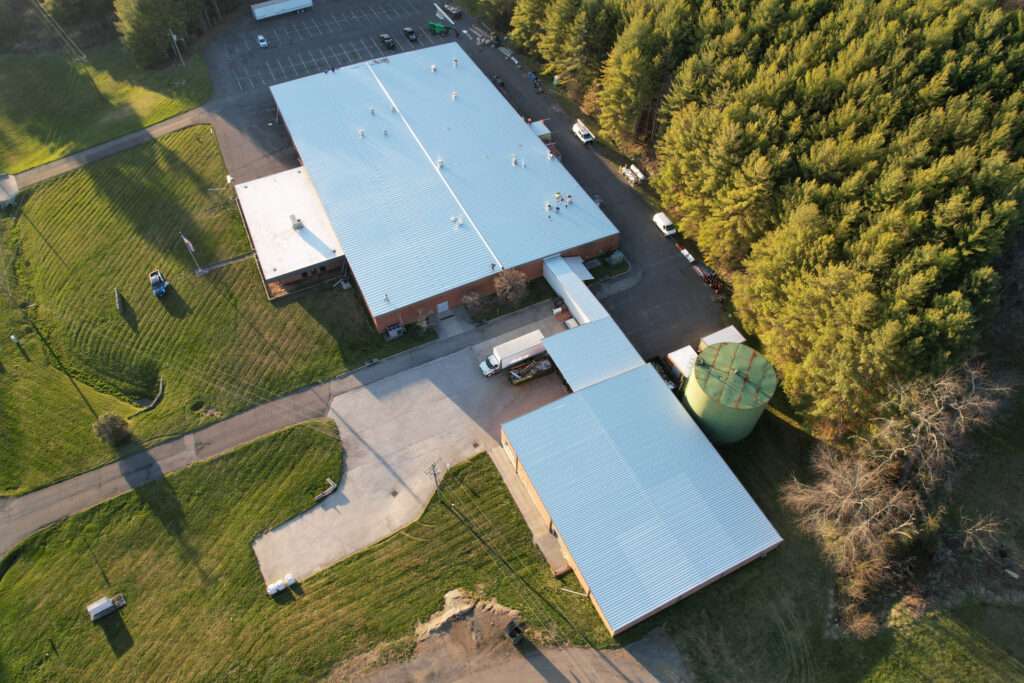 Aerial photo of a pre-engineered metal building surrounded by trees, a metal roof replacement project